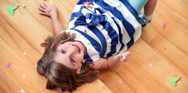 photo of a smiling girl lying on hardwood floor with confetti around her